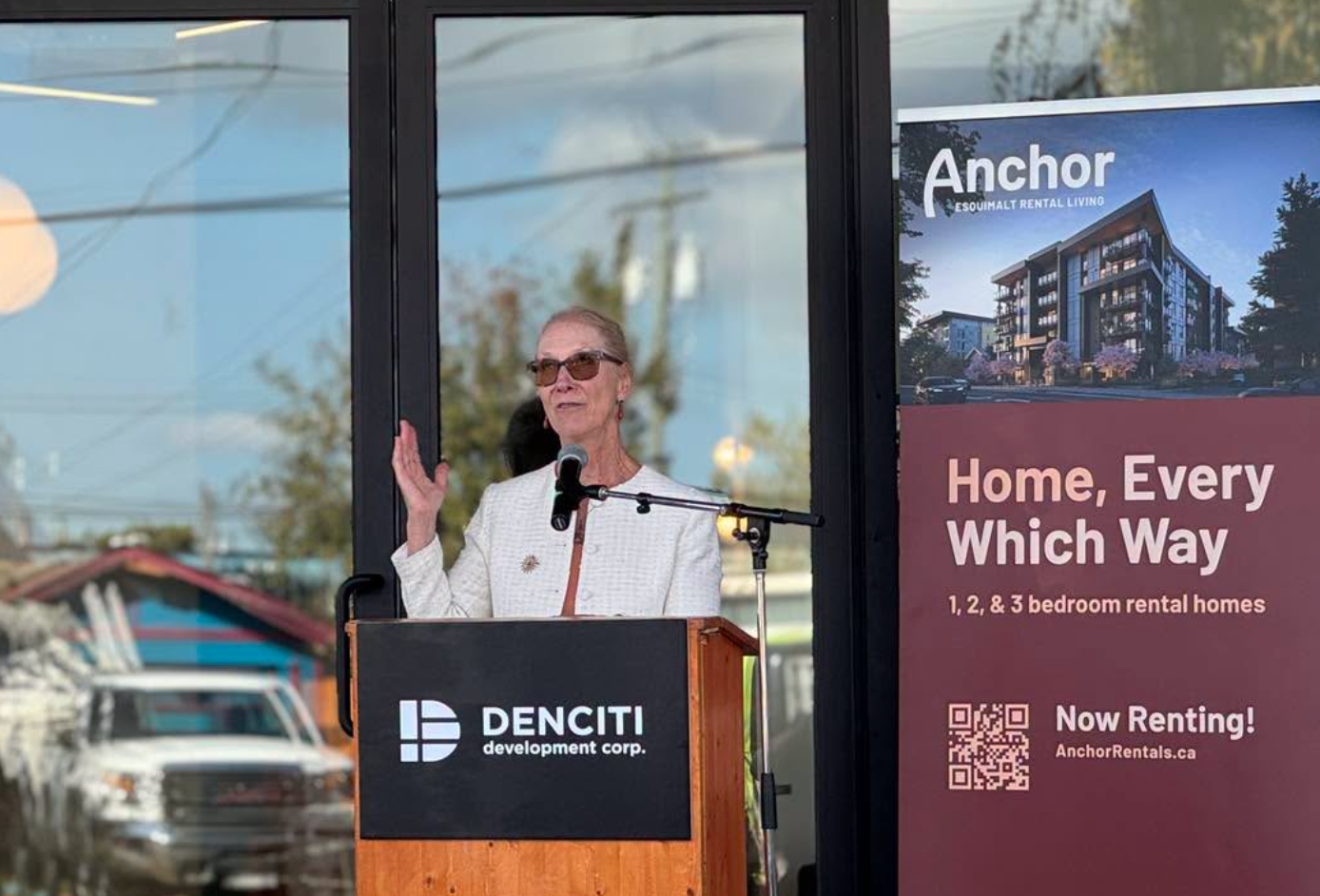 Anchor grand-opening celebration with a speaker at the Denciti podium beside an Anchor rental banner.